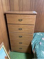 Full view of the five drawer wooden dresser showing side and front with drawer handles