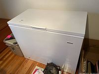 Front and top view of white Kelvinator chest freezer with handle and closed lid.