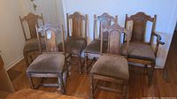 Six Chesley Chair Company oak dining chairs arranged with five straight-backs and one captain's chair in a room with wooden floor.