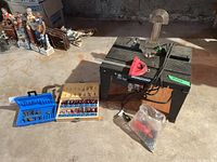 Overall view of the Mastercraft router table with router bits and accessories arranged around it on the floor in a basement setting.