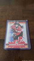 Photo of a Connor McDavid hockey trading card in protective sleeve on wooden surface.