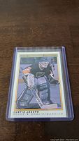Photo of Curtis Joseph rookie hockey card in a protective sleeve on wood surface.