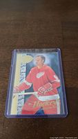 Photo of Gordie Howe hockey trading card in protective plastic case on wooden surface.