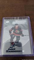 Photo of Jake Sanderson rookie hockey card in protective sleeve, showing front with Smooth Grooves design.