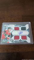 Front view of Jason Zucker rookie card showing four jersey swatches and autograph inside protective case.
