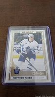 Front side photo of a Matthew Knies rookie hockey card, glossy O-Pee-Chee edition, showing player in Toronto Maple Leafs uniform on ice.