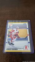 Photo of Sergei Fedorov rookie hockey card in protective plastic case showing player in Detroit Red Wings uniform.