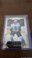Photo of Shane Wright rookie hockey card from Seattle Kraken in protective sleeve on a wooden surface.