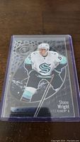 Photo of Shane Wright rookie hockey card in a protective plastic sleeve on wooden surface.