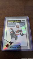 Holographic Tim Stutzle Ottawa Senators rookie hockey card in a protective plastic sleeve shown against a wooden surface.