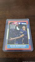 Victor Wembanyama rookie basketball card encased in clear protective sleeve on wooden surface.