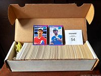 Open box containing a large number of 1989 Donruss baseball cards, fanned out evenly with Ken Griffey Jr. and Randy Johnson rookie cards placed on top.