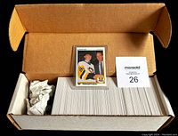 Opened cardboard box containing neatly stacked 1990-91 Upper Deck hockey cards, stored in rows with one card displayed on top showing Pittsburgh Penguins player.