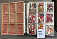 Photo of binder page with football cards arranged in 3x3 grid pockets showing front of cards including Joe Montana, Jerry Rice