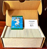 Top view of full box of 1993 Score Select baseball cards with one card standing upright showing player in white uniform pitching baseball.
