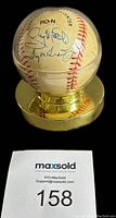 Full view of autographed baseball on custom gold-tone round stand showing some of the signatures including Tug McGraw.