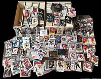 Large lot of hockey cards organized in multiple boxes and binders, some laid out in front showing a wide selection including cards of multiple players, duplicates visible