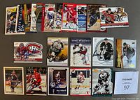 Photo showing 25 different autographed NHL hockey cards arranged in rows on a white surface, featuring multiple players and teams.