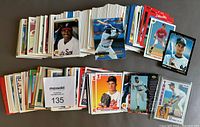 Full overview of the roughly 350 loose baseball rookie and player cards laid out in stacks and spreads, showing a large variety of cards and players included in the lot.