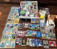 Wide view showing large assortment of loose and boxed baseball cards arranged on floor and table, including sleeved cards and stacks boxed mostly from late 80s and early 90s.