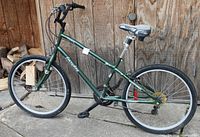 Full side view of the green Everyday Traveler bicycle showing 21-speed gear setup, 26-inch wheels, and black pedals.