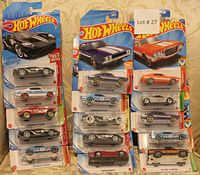 Fifteen Hot Wheels cars in original packaging, arranged in three columns, showing various models and colors including sports and classic cars.