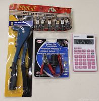 Top view of battery terminal set, battery clip adapter, hand riveter and calculator