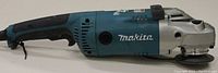 Side view of Makita GA7021 electric angle grinder showing blue body, black handle, and spindle guard.