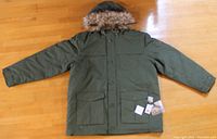 Front view of green hooded winter parka laid flat showing the buttoned front pockets and hood with fur trim.