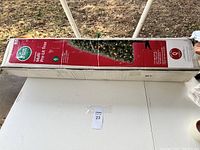 Boxed 6-foot artificial Christmas tree laid horizontally on a white surface outdoors, showing full box length and condition.