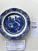 19th century Caughley blue and white porcelain shallow plate featuring a 12 temples pattern with detailed landscape design and scalloped gold-trimmed edges.