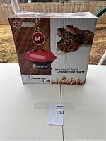 Front view of unopened boxed Uniware 14 inch round charcoal grill, model 1114, showing product image and branding.