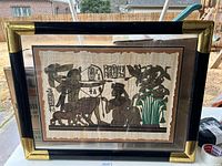 Full view of the framed Egyptian artwork showing two main figures, animals, hieroglyphics, and papyrus plants.