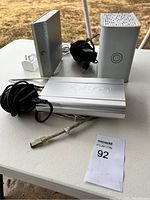 Three electronics items on a white table: a Maxtor external hard drive enclosure, and two vertical networking devices with power adapters.