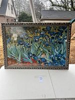 Front view of framed floral artwork featuring blue irises and some white and orange flowers.