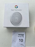 Original white box with Google logo and Nest Thermostat illustration showing temperature set to 70.