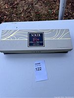 Box of Soleil IR+ infrared flat iron with decorative gold and silver designs on light gray background and central label.