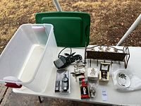 Top view of the holiday lot showing a translucent plastic bin with a green lid, several small holiday decor items, including ornaments, cords, and small dishes.