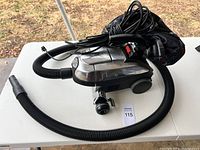 Full view of Kirby canister vacuum cleaner with hose and power cord on a white table outdoors.