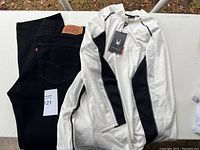 Photo showing the full view of black Levi's jeans and the white/black Spyder long sleeve top laid flat on a surface.