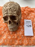 Front view of skull showing intricate designs and septum ring, placed on orange bubble wrap.
