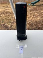 Front view of a black Lasko tower fan heater with control buttons visible on front panel and power cord wrapped at base.