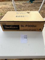 Original brown cardboard box for Technics SL-P300(K) compact disc player showing product name and brand with some tear damage on top.