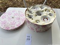 Overall view of the vintage tea set packaged in a floral decorated round box with the lid removed showing cream satin lining and the tea pieces.
