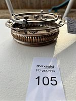 Side angle of the antique wine bottle stand showing copper and silverplate rim detail on a tabletop.