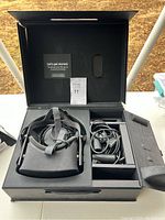 Open box displaying Oculus VR headset, cables, and accessories inside a custom black carrying case.