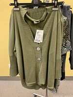 Photo of olive green knit cardigan with tags, hanging on black hanger