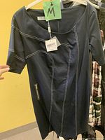 Black dress with white contrast topstitching, side zip, elbow-length sleeves and designer label visible, tagged size medium