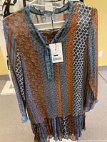 Front view of pleated skirt and matching blouse with vertical mixed pattern stripes in brown, blue, white