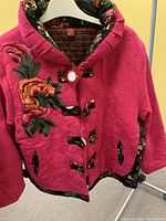 Pink floral embroidered jacket front with toggle closures and floral trim